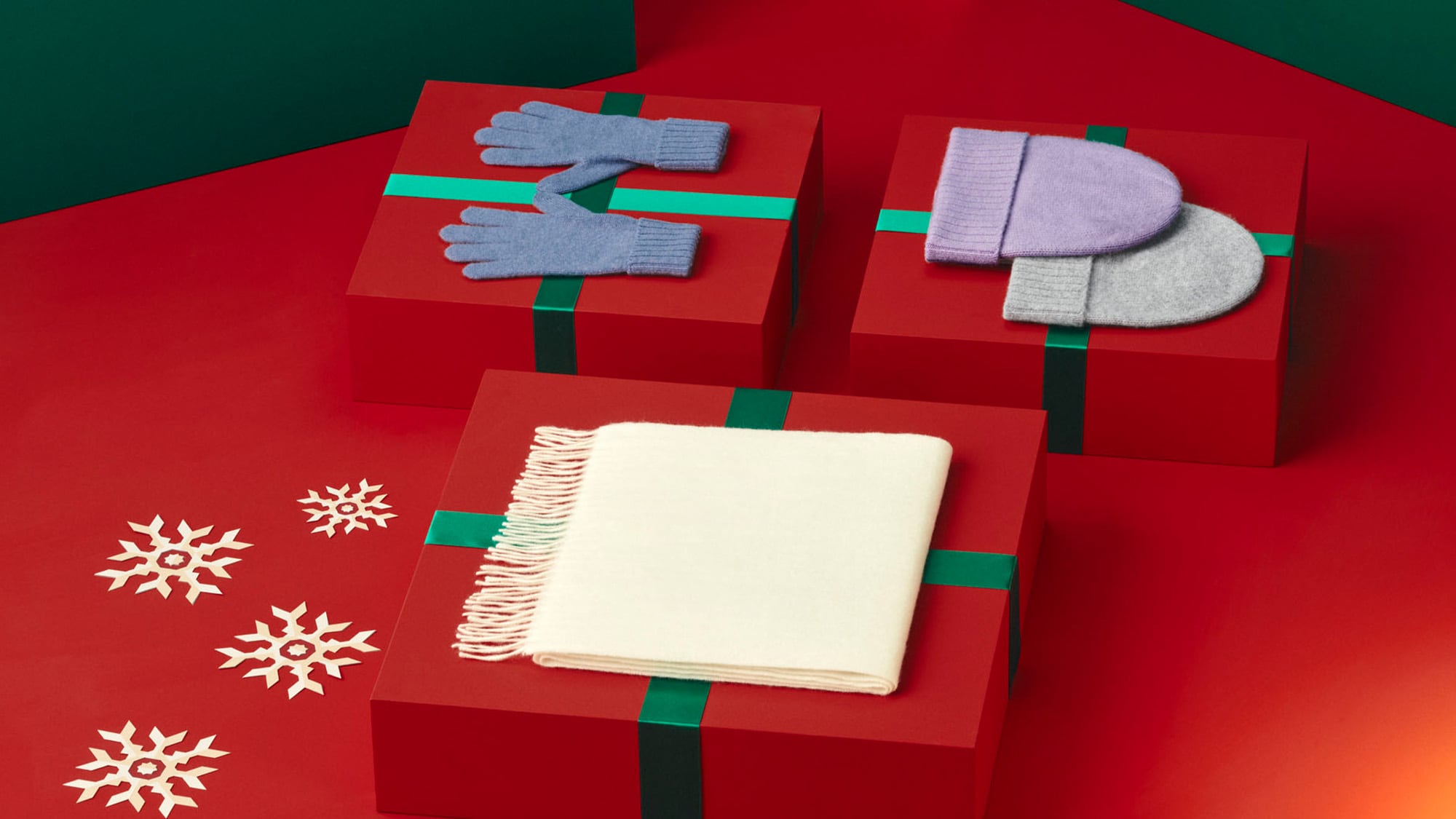 ein Schal, eine Mütze und Handschuhe, die auf Geschenkboxen liegen