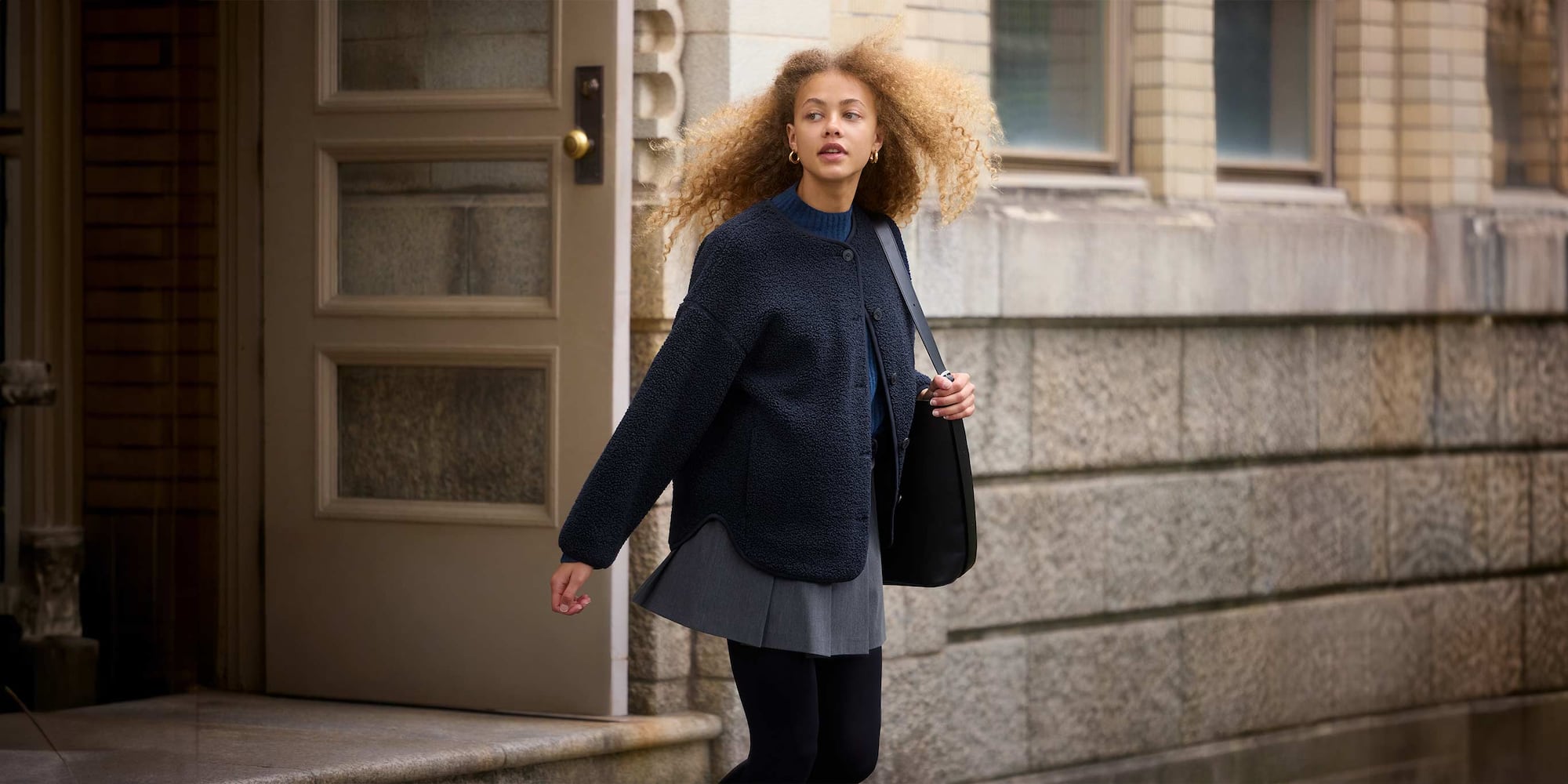 model wearing Pile Lined Fleece Relaxed Cardigan in navy over a blue knit, grey skort and black tights