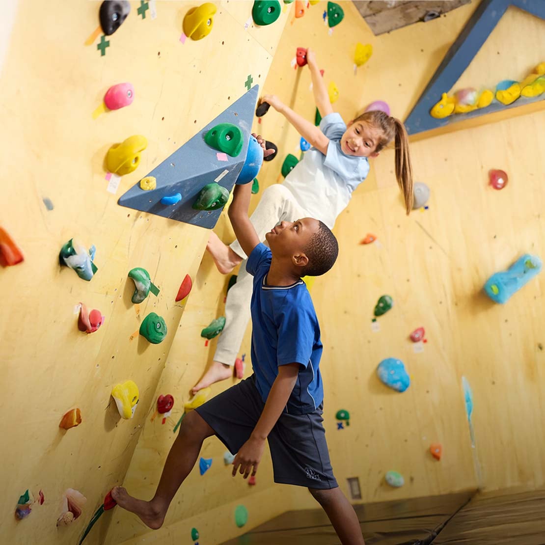 two models wearing uniqlo activewear while climbing at an indoor climbing wall