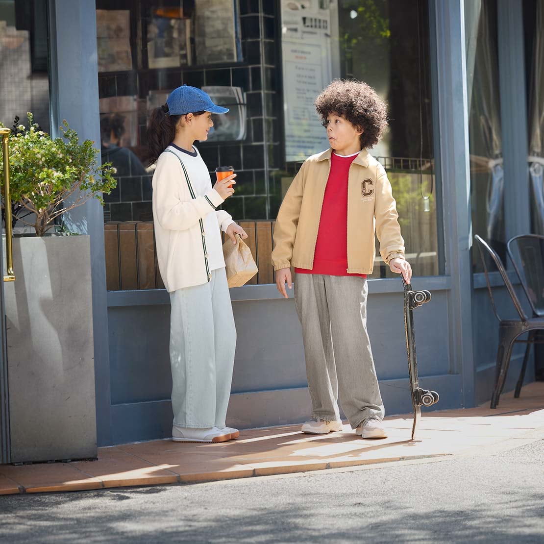 two models wearing UNIQLO jeans while standing outside a café