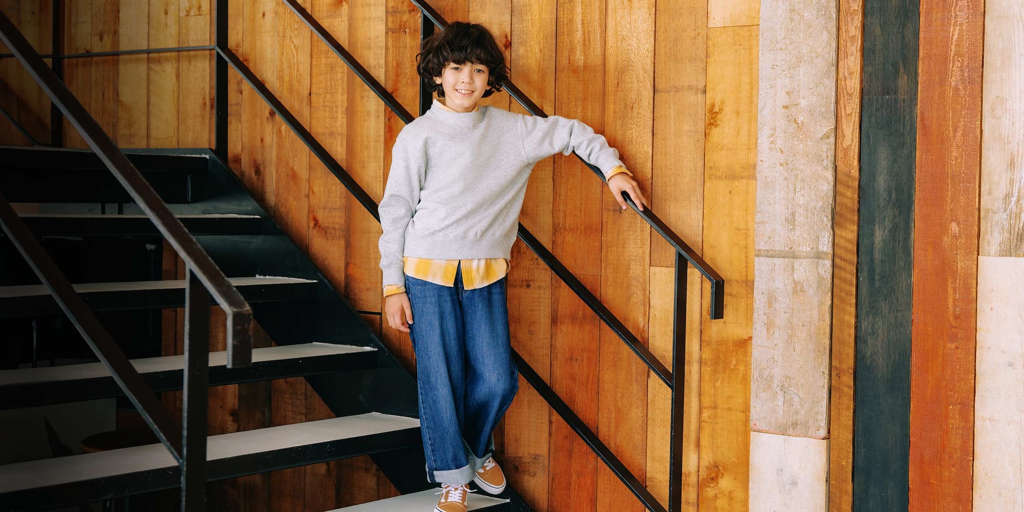 le mannequin porte un jean droit large bleu avec une chemise à carreaux jaune et un pull gris